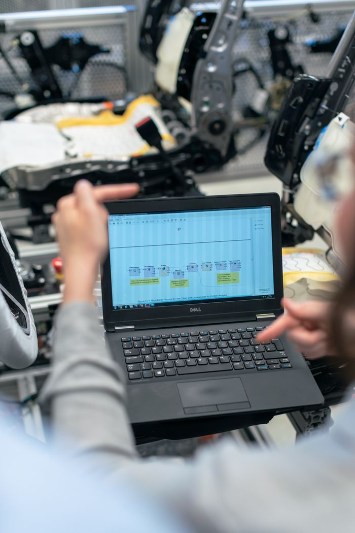 services-03 Engineers using a laptop to analyze software data in an industrial workshop setting.