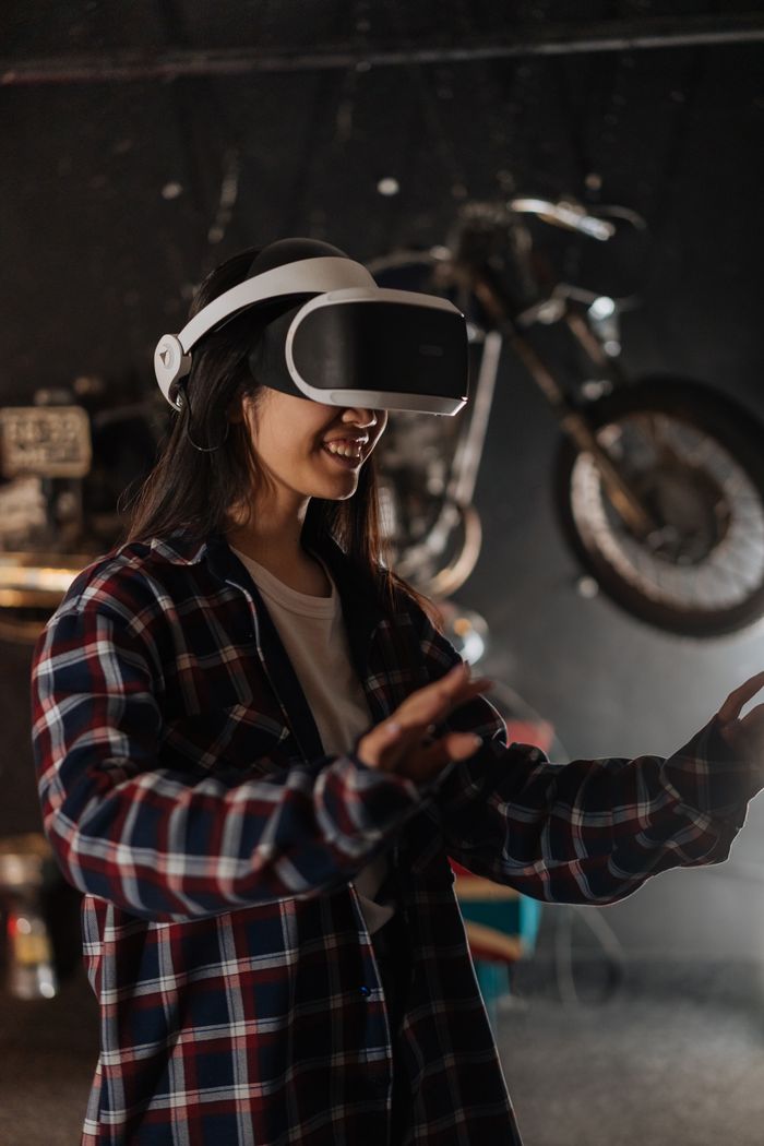 why-choose-us A woman wearing VR goggles immersed in a virtual reality game indoors.